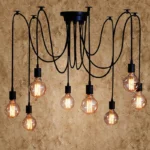 Retro spider chandelier with multiple black metal arms and white shades against a dark wall