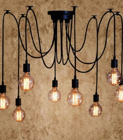 Retro spider chandelier with multiple black metal arms and white shades against a dark wall