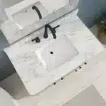 The bathroom vanity's sink basin with a single-hole faucet, set against a tiled wall.