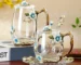 Elegant crystal glass tea mug with enamel floral design and handgrip on a wooden table