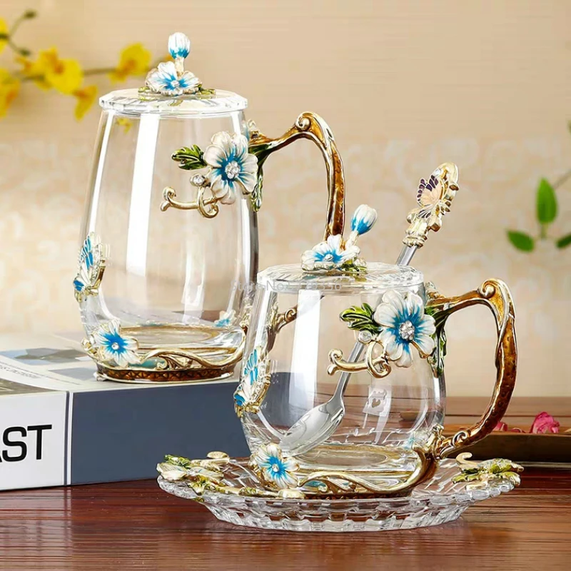 Elegant crystal glass tea mug with enamel floral design and handgrip on a wooden table