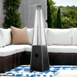 Goldoma black steel and stainless steel patio heater against a brick wall in a cozy backyard setting.