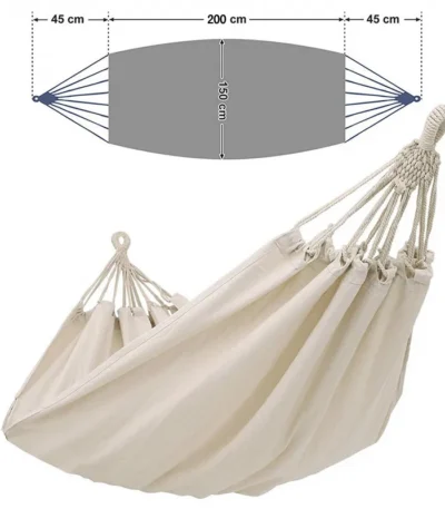 Double hammock for patio with cotton fabric and wooden spreader bars in a garden setting