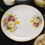 Elegant bone china dinnerware set with plates, bowls, and soup spoons on a wooden table