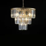 Luxury 3-tier crystal chandelier illuminated in a dimly lit dining room, casting sparkles on the table below.