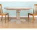 Round solid wood dining table with natural finish and pedestal base in a modern dining room