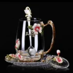Elegant crystal glass tea mug with enamel floral design and handgrip on a wooden table