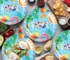 Blue disposable party plates set with cups, napkins, and cutlery arranged on a festive table