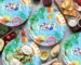 Blue disposable party plates set with cups, napkins, and cutlery arranged on a festive table