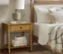 Natural wood nightstand with drawer and shelf in a cozy bedroom setting