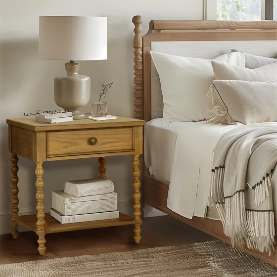 H47ff9bfba6314f7694285d64dde55f89K.webp Natural wood nightstand with one drawer and a shelf beside a bed in a bedroom