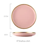 Elegant dinnerware set with gilt rim pink porcelain plates, bowls, mugs, and cutlery on a table
