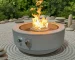 Galvanized steel outdoor fire pit with natural gas flame on a patio
