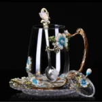 Elegant crystal glass tea mug with enamel floral design and handgrip on a wooden table