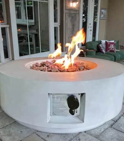 30-inch round propane fire pit table in grey color on a patio with cushions