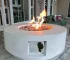 30-inch round propane fire pit table in grey color on a patio with cushions