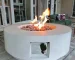 30-inch round propane fire pit table in grey color on a patio with cushions