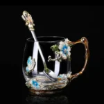Elegant crystal glass tea mug with enamel floral design and handgrip on a wooden table