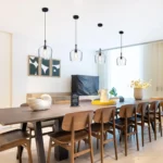 Modern black pendant light illuminating a dining table, with seeded glass diffusing soft light.
