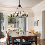 The chandelier lit in a dim room, with candles glowing against the black metal frame and wood accents