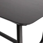 Mid-century modern dining table with black ash veneer top and trestle base in a dining room setting