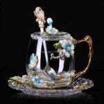 Elegant crystal glass tea mug with enamel floral design and handgrip on a wooden table