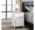 White nightstand with drawer and cabinet in a modern bedroom setting