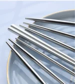 Elegant stainless steel flatware set with forks, spoons, and knives arranged on a wooden table