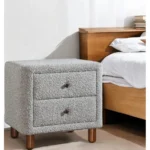 Gray boucle nightstand with two drawers and wooden legs in a modern bedroom setting
