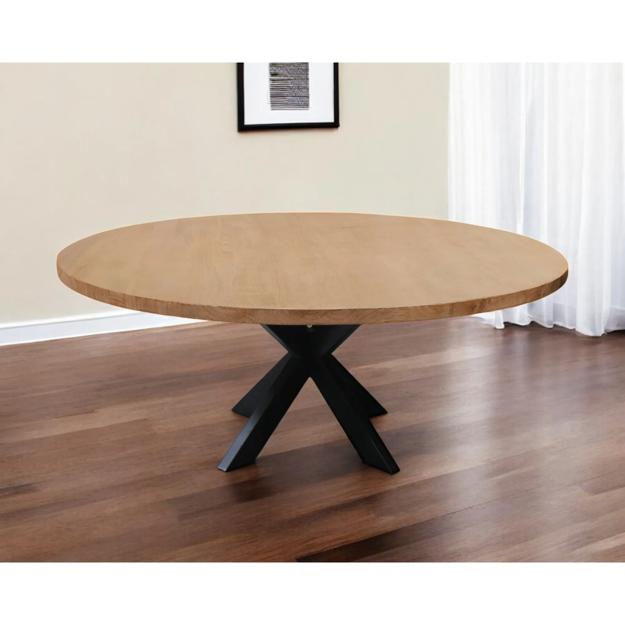 Rustic round dining table with natural acacia wood top and black iron pedestal base in a farmhouse dining room