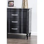 Black solid wood nightstand with curved front and turned legs in a bedroom setting