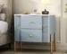 Modern fluted nightstand with drawers featuring golden metal handles and legs in a bedroom setting