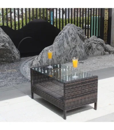 Outdoor coffee table with clear tempered glass top and brown PE rattan frame on a patio