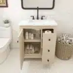 Vanity with sink installed, paired with a rectangular mirror and sconces, in a hotel-style bathroom.