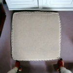White striped storage ottoman in living room with books and decor on top