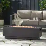 Outdoor propane fire pit in dark grey rectangular iron with glowing flames