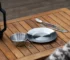 Outdoor dinnerware set with plates, bowls, and cups arranged on a picnic table