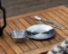 Outdoor dinnerware set with plates, bowls, and cups arranged on a picnic table