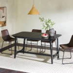 Mid-century modern dining table with black ash veneer top and trestle base in a dining room setting