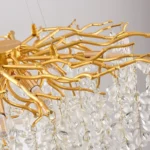 Gold crystal chandelier hanging in modern dining room with golden light reflections