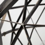 The HMS pendant light suspended at eye level, revealing the open cage structure and matte black finish.