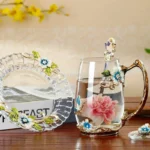 Elegant crystal glass tea mug with enamel floral design and handgrip on a wooden table