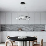 A side-angle shot showing the black chandelier's slim profile and the remote control next to it on a table, with a