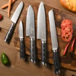 Damascus steel knife set with Pakka wood handles and wooden knife holder on a cutting board