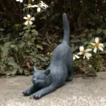 Hand-painted stretching cat statue in garden setting