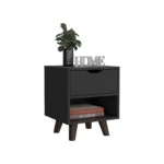 Modern nightstand with drawer and open shelf in black finish with wooden legs on a bedroom floor next to a bed