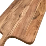Large wooden cutting board with knife and cheese on a kitchen counter