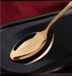 24-piece stainless steel cutlery set with gold handles displayed on a wooden table