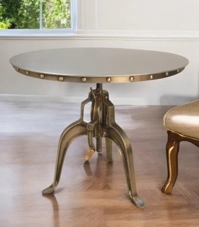Adjustable height round dining table with antiqued nickel three-leg pedestal base and rivet detailing