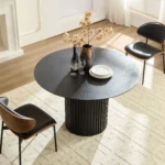 Mid century dining table round black MDF with four chairs in a modern dining room